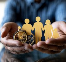 Protecting the Family: Hands gently cradling a family cutout, including a wheelchair symbol, representing inclusivity and care.  A symbol of family support and accessibility.
